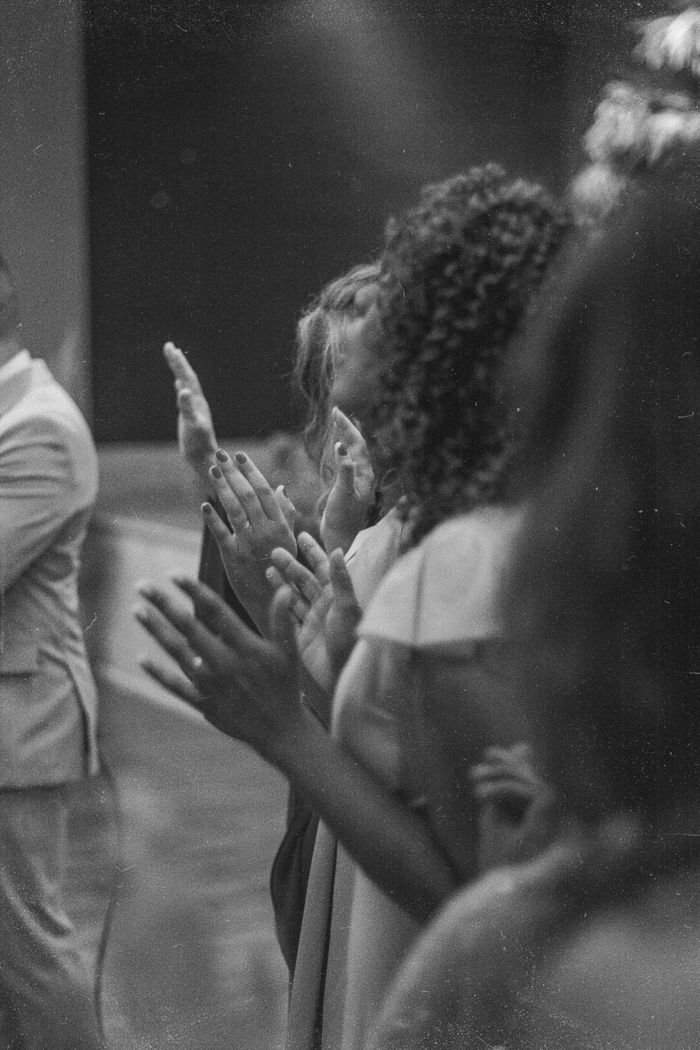 Women in grayscale image worshipping together with hands raised.
